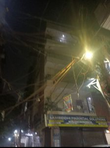 गली में लटकी हुई अव्यवस्थित बिजली की तारे और रात में दिखता हुआ खतरा 